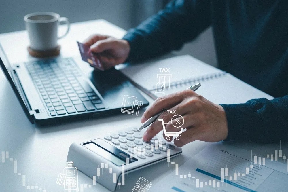 Persoană care lucrează la un laptop, analizând plăți și taxe, concept legat de TVA în Marea Britanie.